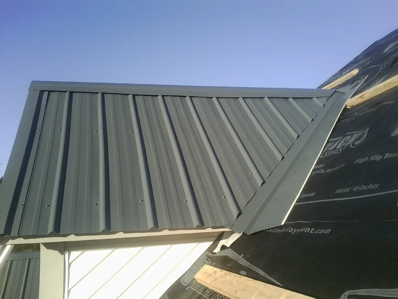 Gray metal roof panels going on over a garage gable in Germanton
