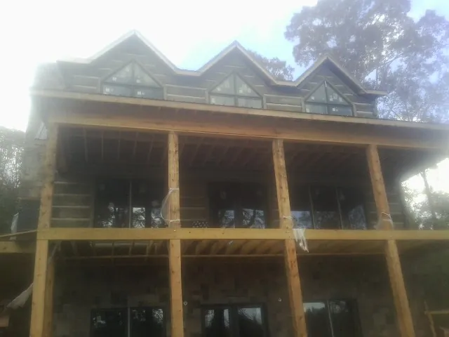 Dormers and porch framing on a large log home under construction — Roof Coating work by our crew in Germanton