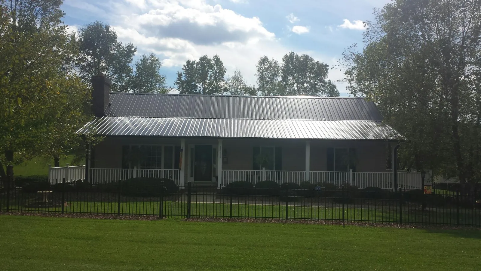 Gray metal roof on a brick ranch with a full width front porch — Gutter Guard Installation work by our crew in Germanton
