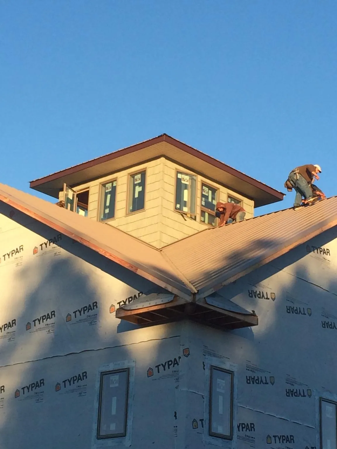 Roofers working around a rooftop cupola on a new metal roof at sunset — Roof Waterproofing in Germanton by Roofing Brothers